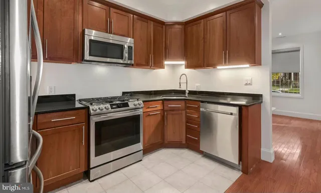 a kitchen with stainless steel appliances granite countertop a stove a microwave and a white cabinets