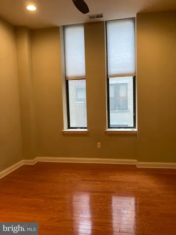 a view of empty room with wooden floor and fan