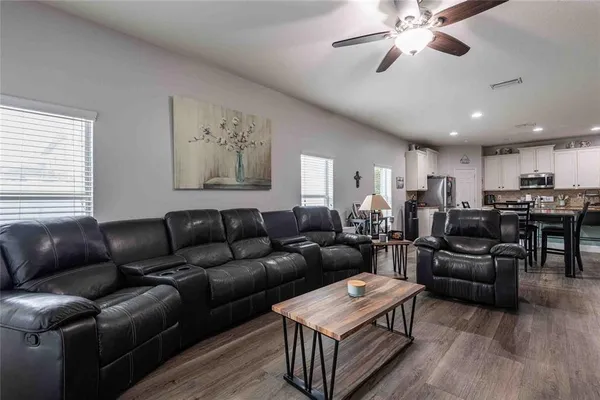 a living room with furniture kitchen view and a wooden floor