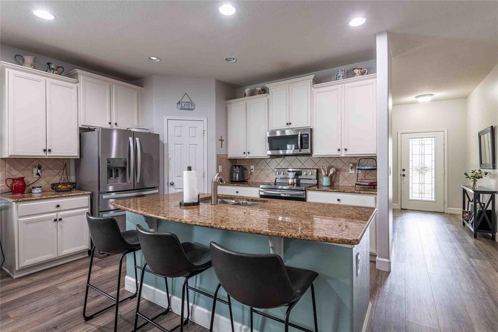 2814 Maple Brook Loop Lutz, FL 33558 - Photo 5 of 38 a kitchen with stainless steel appliances granite countertop a stove a sink a microwave a refrigerator white cabinets and wooden floor