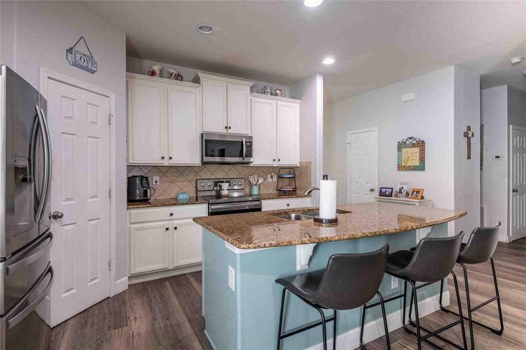 2814 Maple Brook Loop Lutz, FL 33558 - Photo 6 of 38 a kitchen with stainless steel appliances granite countertop a stove top oven a refrigerator a sink and white cabinets with wooden floor