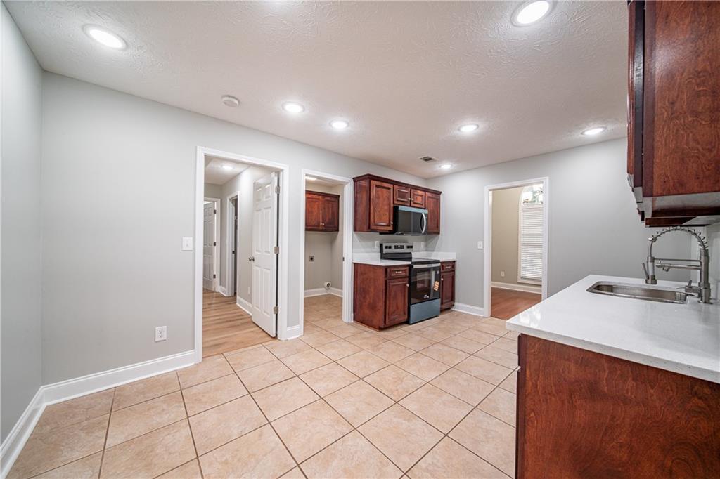 1927 Lee Road Salem, AL 36874 - Photo 20 of 45 Kitchen with light tile patterned floors, appliances with stainless steel finishes, a textured ceiling, recessed lighting, and light stone countertops