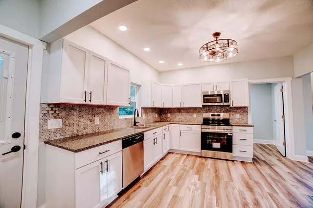 a kitchen with kitchen island granite countertop a sink cabinets and window