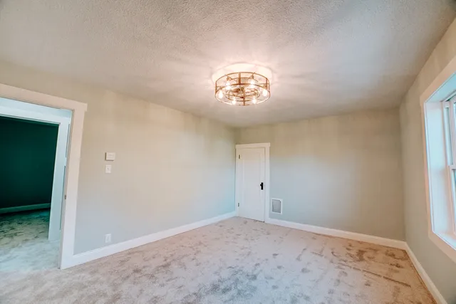an empty room with a chandelier fan and windows