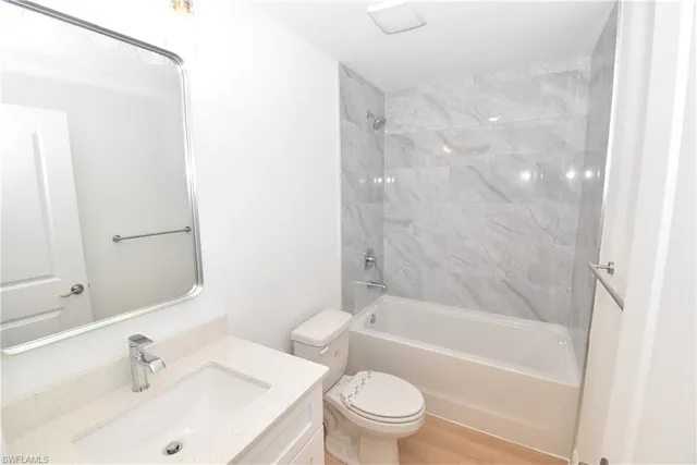 a bathroom with a bathtub shower sink mirror vanity and toilet