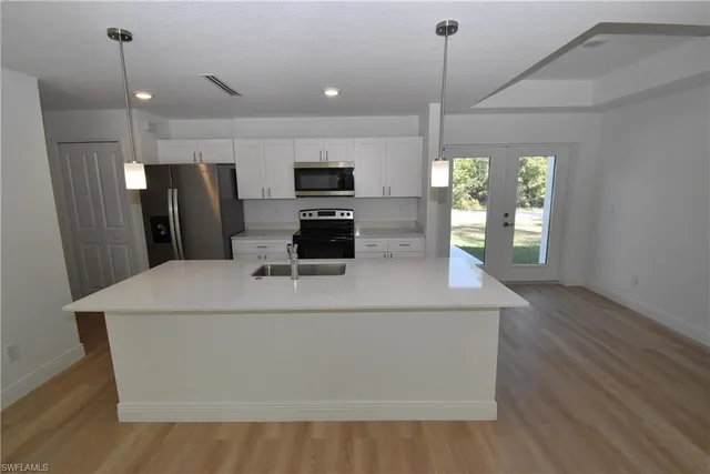 a kitchen with kitchen island a counter top space appliances and a window