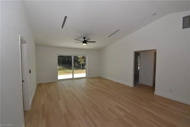 a view of an empty room with a window and wooden floor