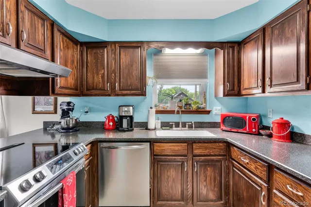a kitchen with stainless steel appliances granite countertop a refrigerator sink and wooden cabinets
