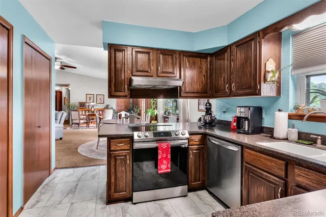 a kitchen with stainless steel appliances granite countertop a stove a sink dishwasher and cabinets with wooden floor