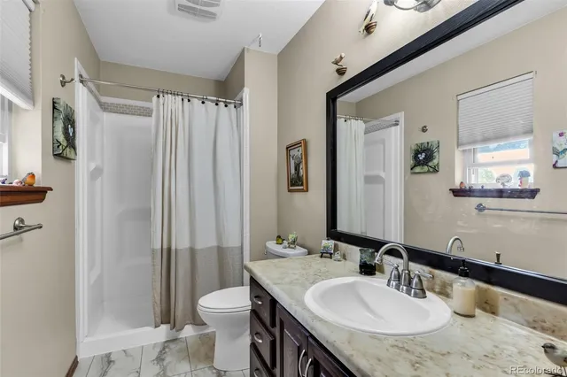 a bathroom with a granite countertop sink toilet and shower