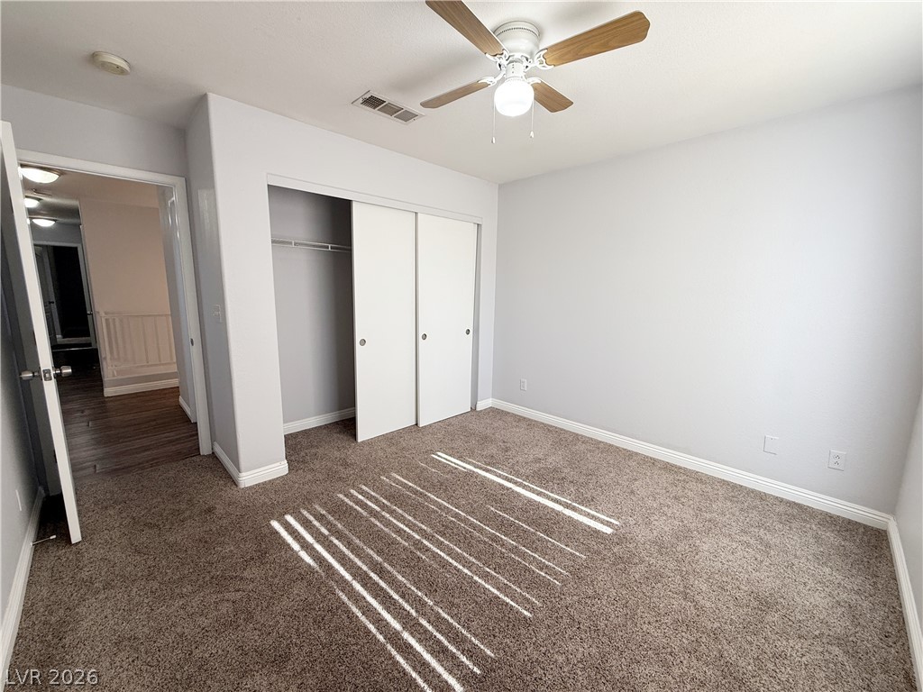 2185 Polynesia Circle Henderson, NV 89074 - Photo 21 of 37 A comfortable bedroom features carpet flooring, sliding closet doors, and a ceiling fan.