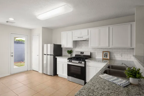 a kitchen with stainless steel appliances granite countertop a stove a refrigerator and a sink