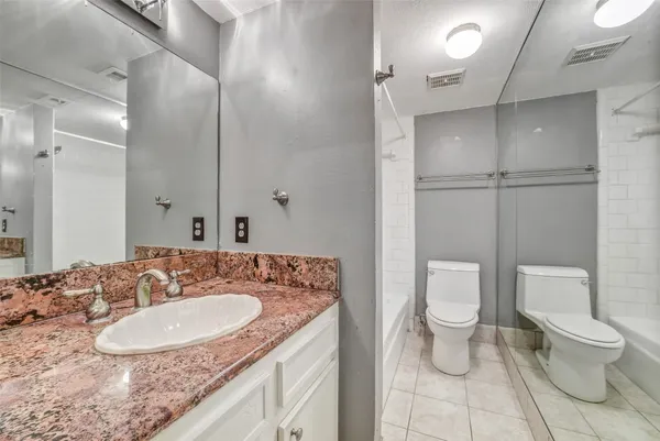 a bathroom with a granite countertop sink toilet a mirror and shower