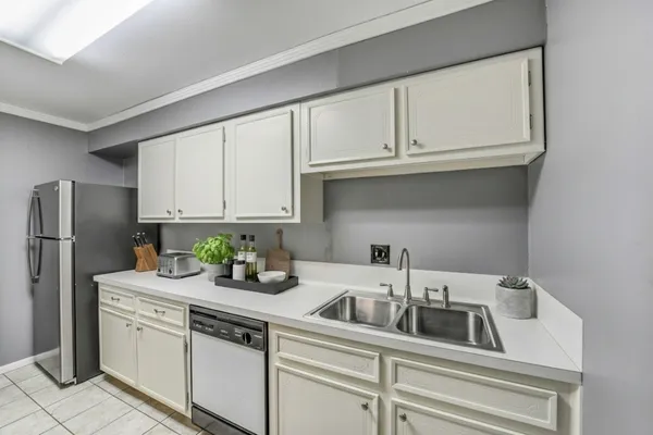 a kitchen with stainless steel appliances granite countertop white cabinets a refrigerator and a sink