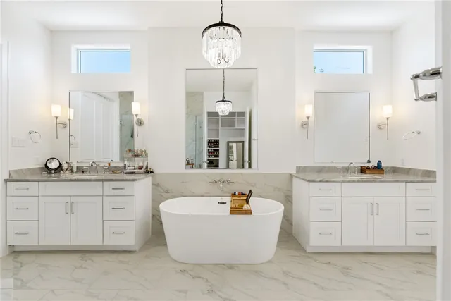 a spacious bathroom with a granite countertop double vanity sink a mirror and a bathtub