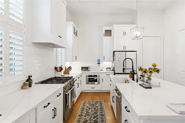 a kitchen with sink a stove and white cabinets with wooden floor