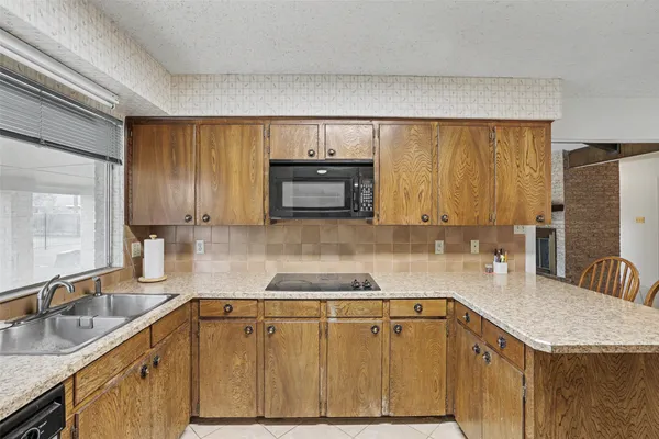 a kitchen with granite countertop a sink a stove cabinets and refrigerator