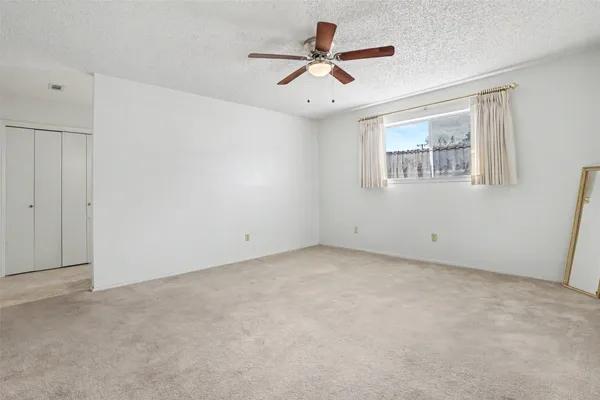 an empty room with a ceiling fan and window