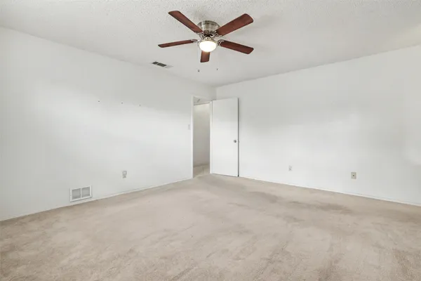 an empty room with closet and a ceiling fan