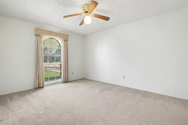 an empty room with windows and fan
