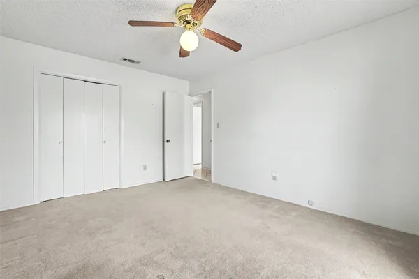 an empty room with a window and a fan