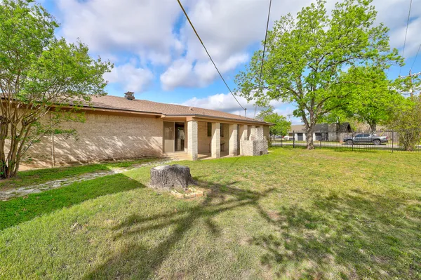 a view of a house with a yard and a large tree