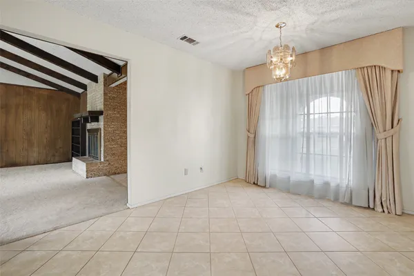 an empty room with chandelier fan and windows
