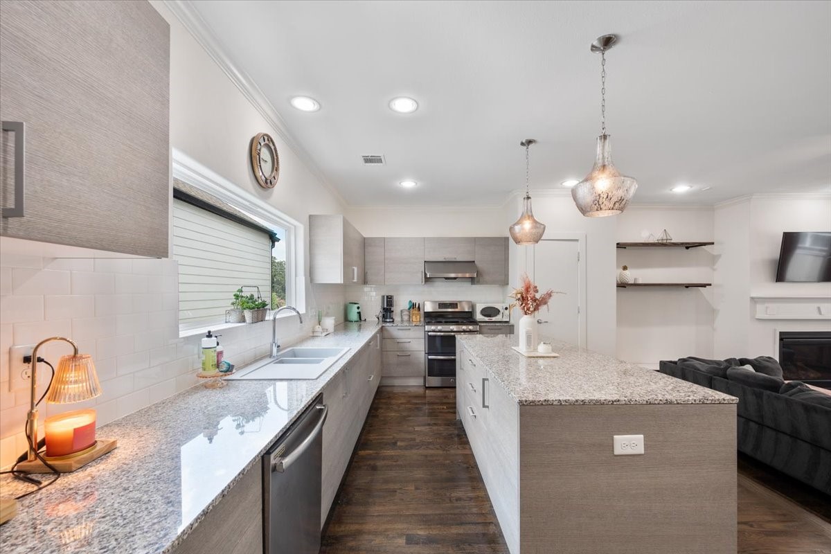 1333 West 22nd Street, Unit F Houston, TX 77008 - Photo 3 of 22 a large kitchen with stainless steel appliances kitchen island granite countertop a sink a stove and a wooden floors
