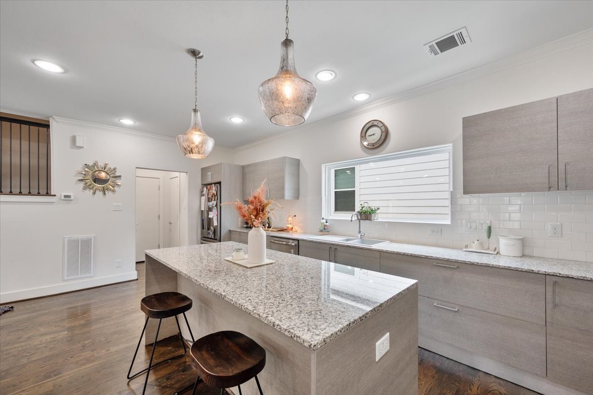 1333 West 22nd Street, Unit F Houston, TX 77008 - Photo 4 of 22 a kitchen with granite countertop a sink a center island and cabinets
