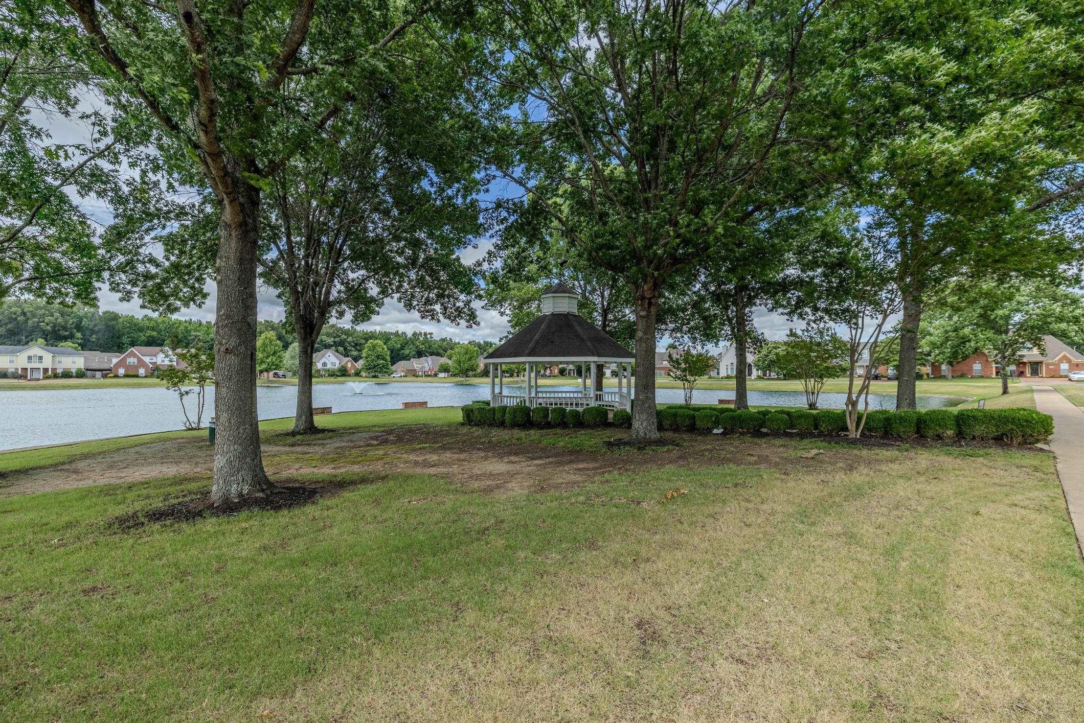 96 Berryfield Cove Collierville, TN 38017 - Photo 36 of 39 Expansive lawn featuring mature trees and a lakeside white gazebo with a dark roof