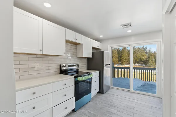 a kitchen with stainless steel appliances granite countertop a stove a sink and white cabinets