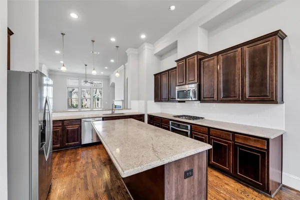 a kitchen with kitchen island granite countertop wooden cabinets and stainless steel appliances