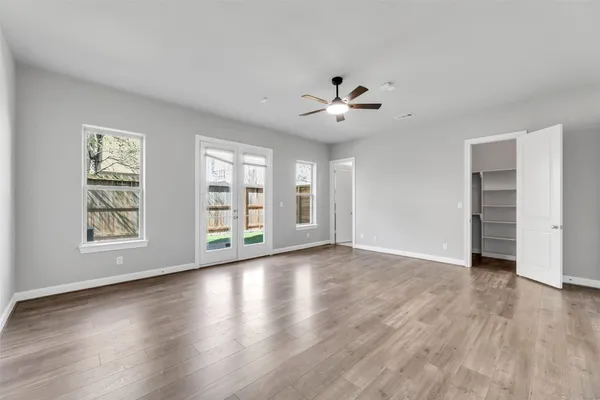 a view of an empty room with a window and wooden floor