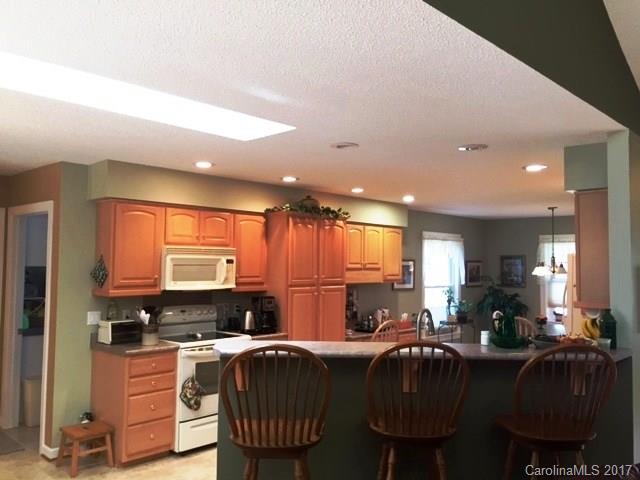 61 Bowman Ridge Road, Unit 5 Hendersonville, NC 28739 - Photo 9 of 24 a kitchen with stainless steel appliances granite countertop a stove top oven a sink dishwasher a dining table and chairs with wooden floor