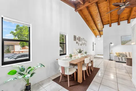 a dining room with furniture a rug a potted plant and a large window