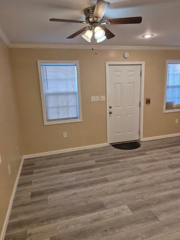 a view of an empty room with window and wooden floor