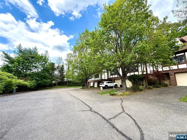 a front view of a house with a garden and tree