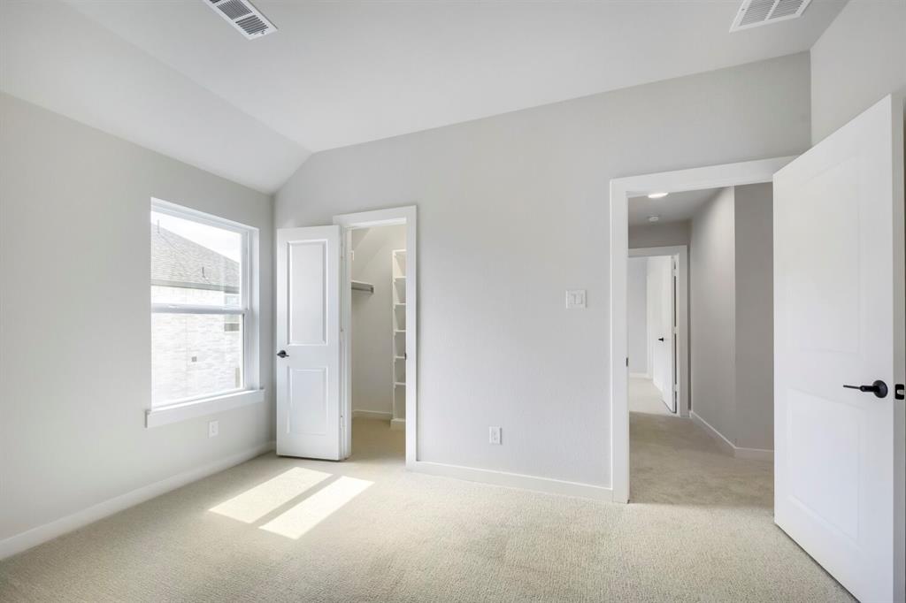 800 Blackberry Road Haslet, TX 76052 - Photo 16 of 28 Vaulted ceiling bedroom with light-toned carpet flooring, a double-hung window, and a walk-in closet featuring shelving