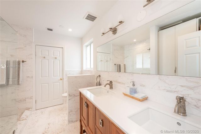 a bathroom with a sink vanity granite tub shower and a mirror