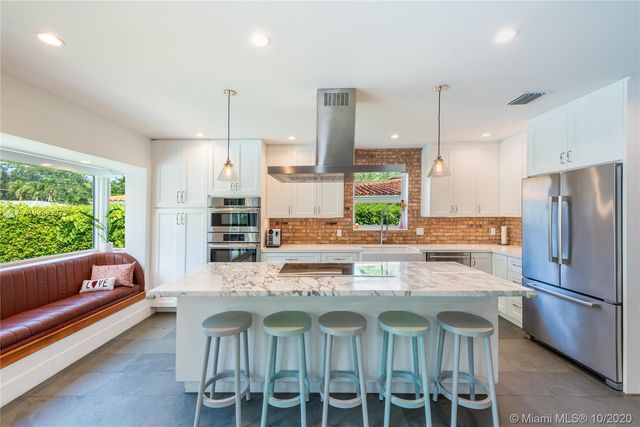 a kitchen with stainless steel appliances granite countertop a kitchen island a stove and a refrigerator