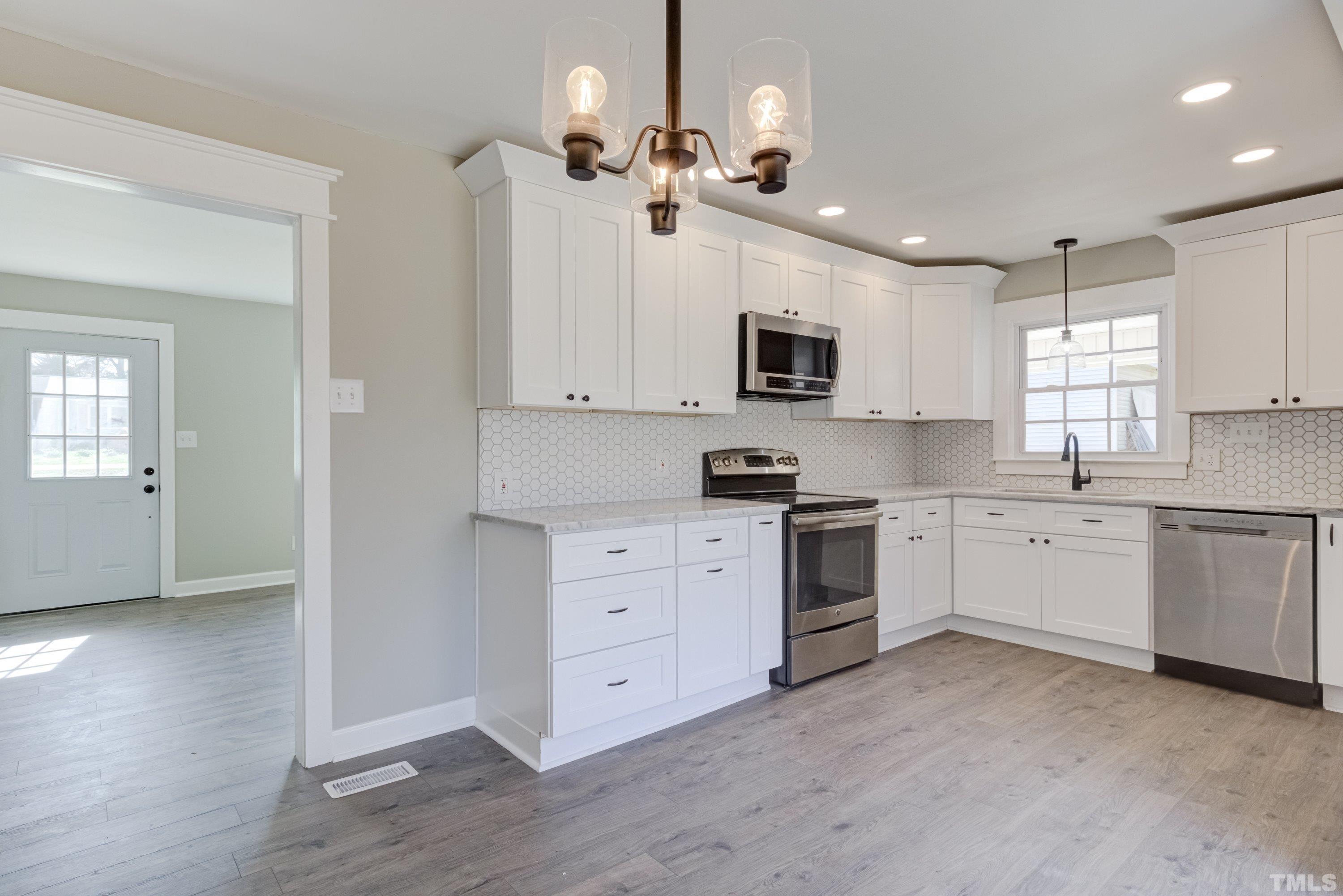 5809 Neuse Street Raleigh, NC 27610 - Photo 5 of 19 a kitchen with stove a sink and white cabinets
