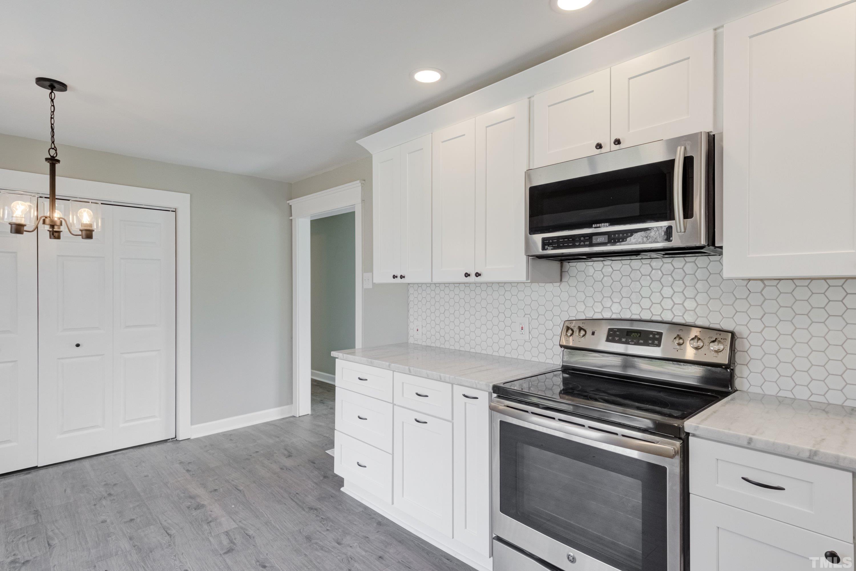 5809 Neuse Street Raleigh, NC 27610 - Photo 6 of 19 a kitchen with stainless steel appliances white cabinets and a stove top oven