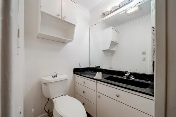 a bathroom with a granite countertop toilet and sink
