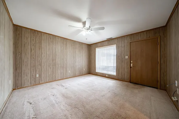 an empty room with windows and fan