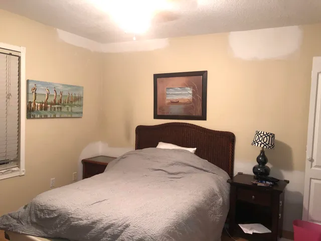 a bedroom with a bed and a lamp on dresser