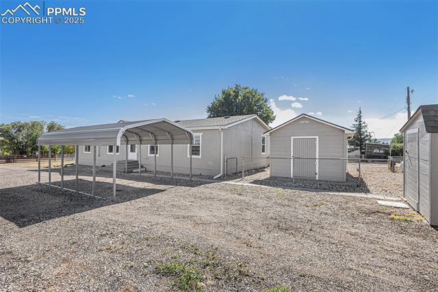 8440 Piute Road Colorado Springs, CO 80926 - Photo 3 of 34 Open and welcoming front area with detached covered carport, sheds, and extra parking—all set against the backdrop of breathtaking Cheyenne Mountain views.