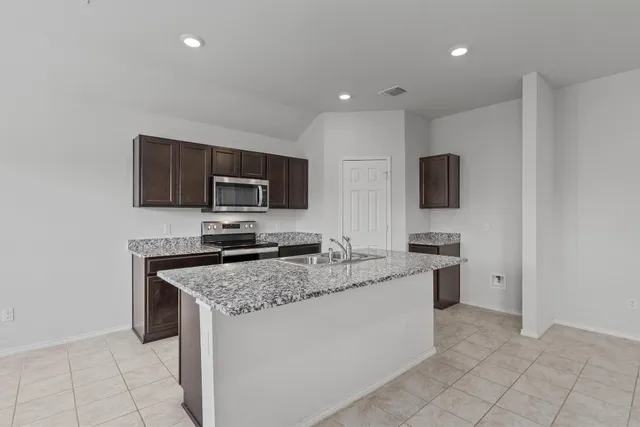 a kitchen with stainless steel appliances granite countertop a stove top oven a sink a microwave and a refrigerator