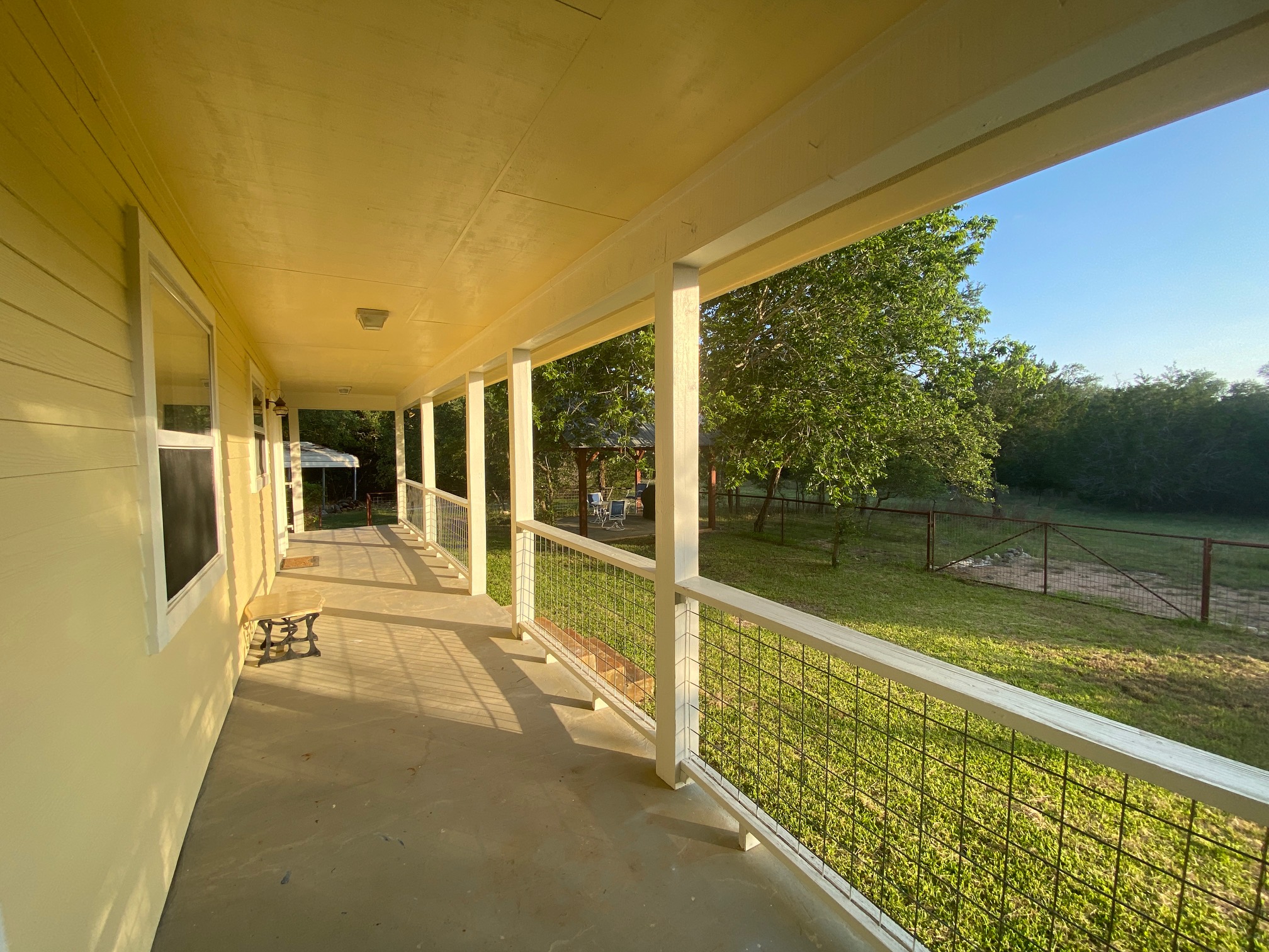 306 Plainview Road Wimberley, TX 78676 - Photo 20 of 29 A tranquil covered porch offers views of the verdant yard and distant trees, perfect for relaxation.