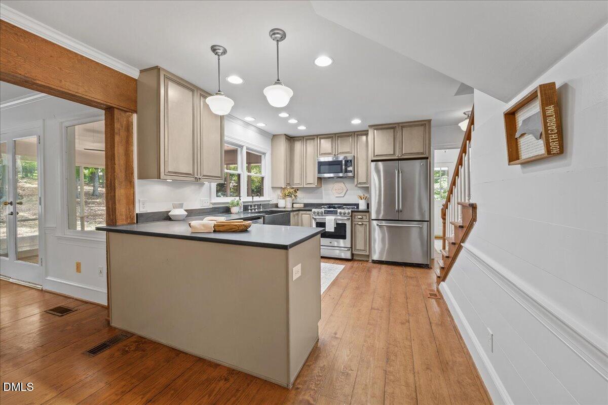 6516 Bakersfield Drive Raleigh, NC 27606 - Photo 21 of 59 a kitchen with granite countertop a refrigerator a sink dishwasher a stove and white cabinets with wooden floor
