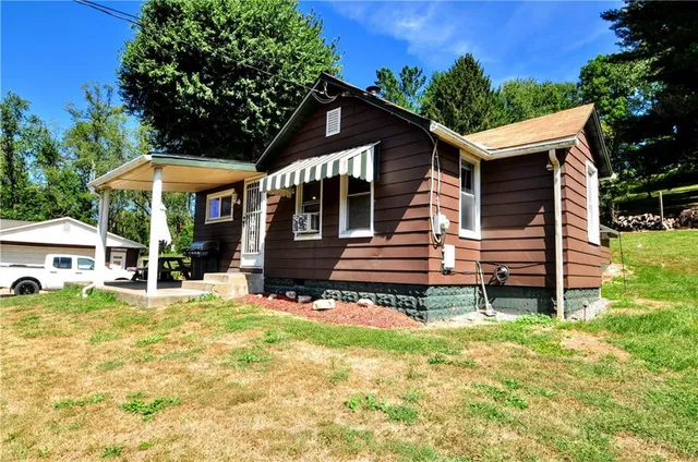 a view of a house with a yard and lawn chairs with a fire pit